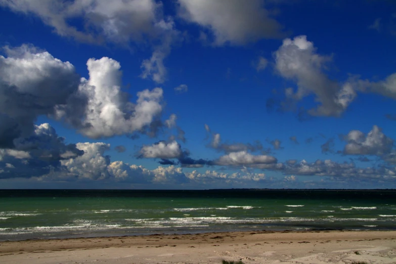 a view of the ocean with many clouds in it