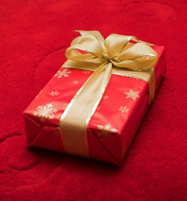 a small red wrapped present box sitting on a red surface