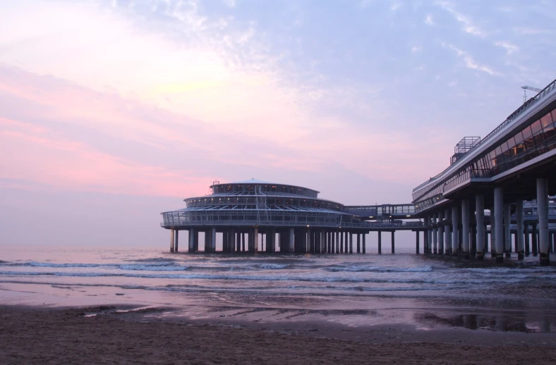 two big piers sit near the beach as the sun sets