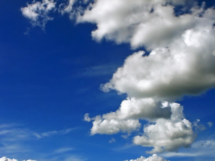 large fluffy white clouds float across the blue sky