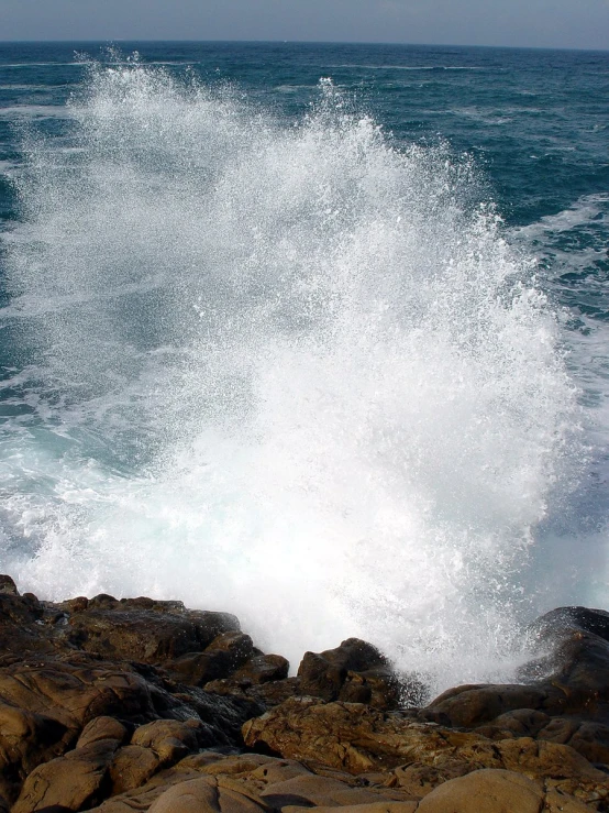 water crashing onto rocks in front of an ocean