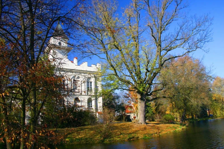 a white house next to a lake in autumn