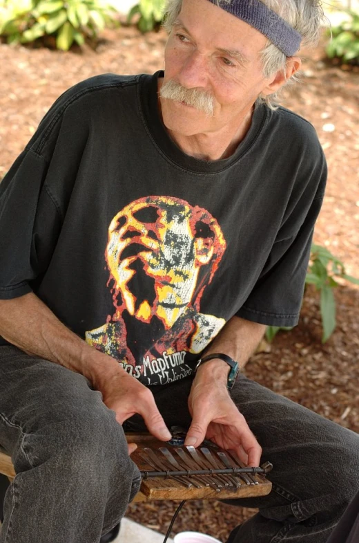 a man holding a piece of wood sitting on top of his lap