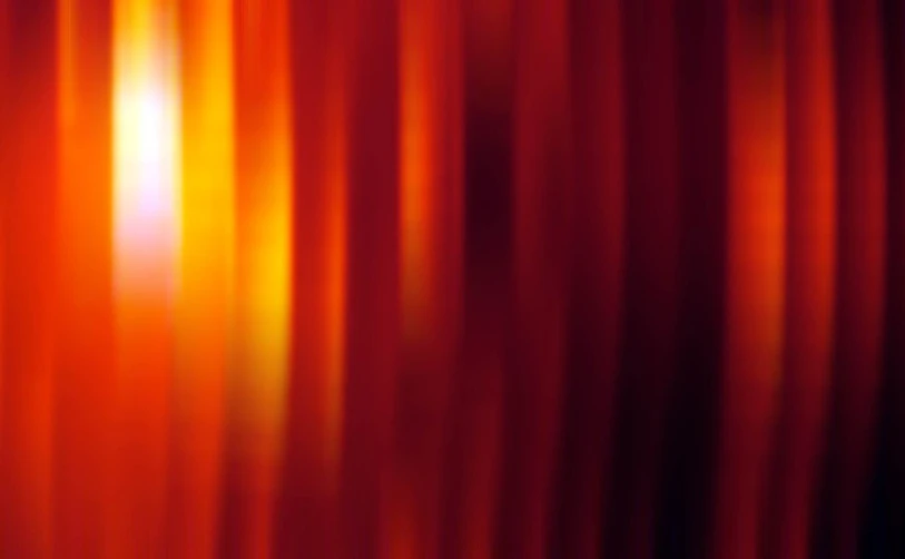 a red curtain with a black background and light reflection
