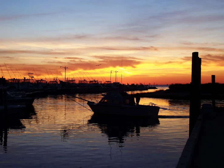 boats sit docked in the harbor at sunset