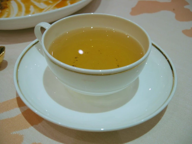a white cup of soup sits in the center of a small plate