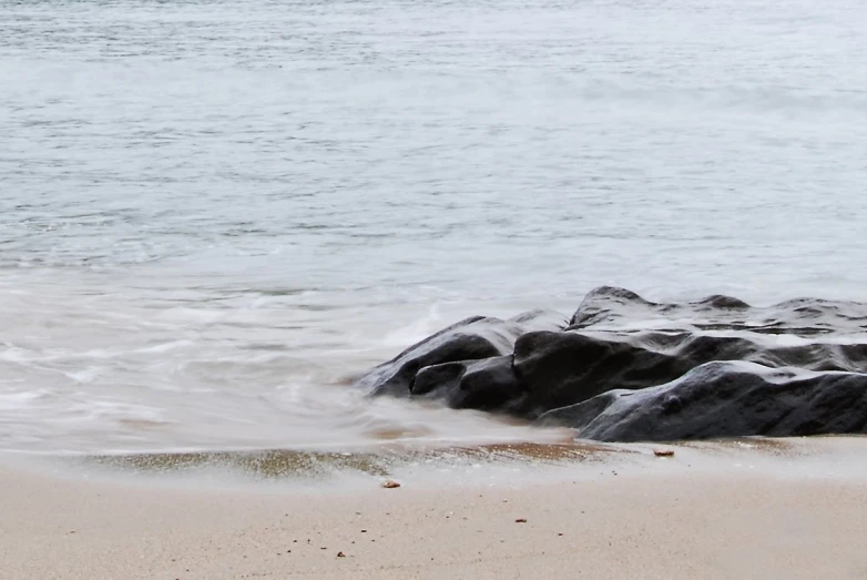 the wave crashes over the rocks at the beach