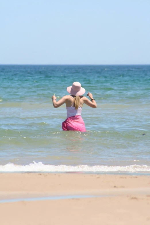 a woman with a pink bikini and a hat on a beach