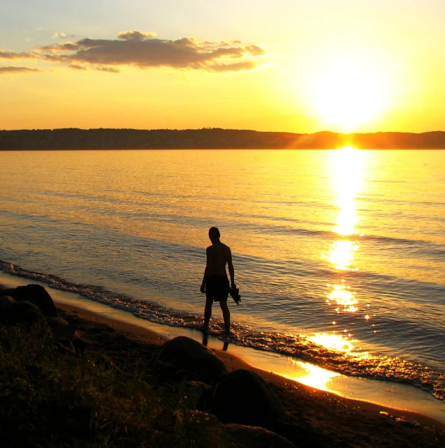 a man standing on the beach watching the sun rise