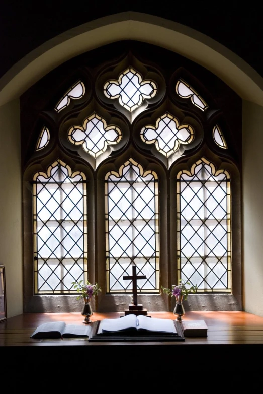 a view looking into a chapel at a cross and two stained glass windows