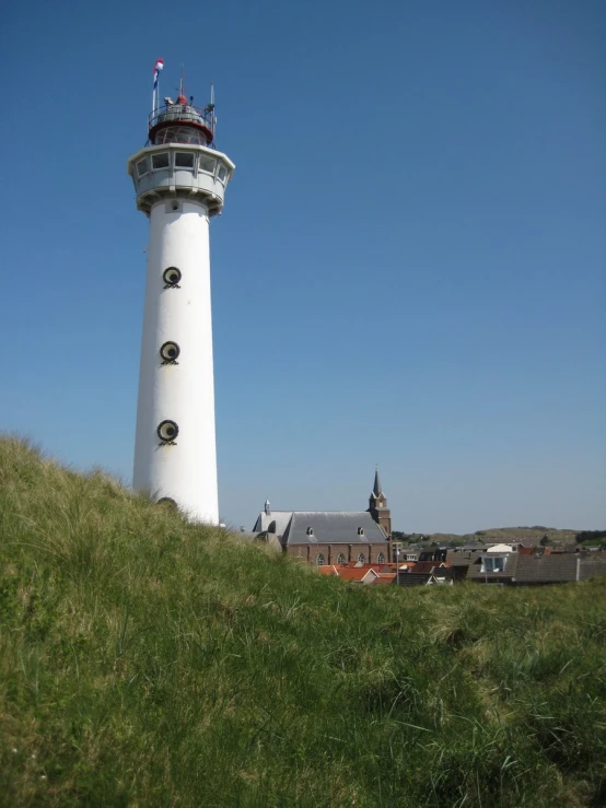 a white light house on a hill, with green grass