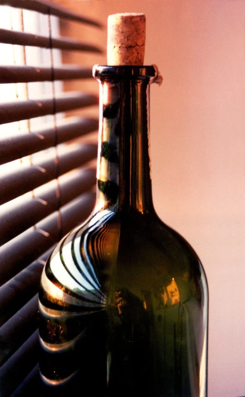 a bottle with a cork sitting in front of a window