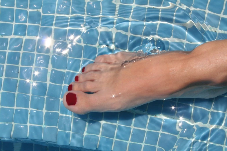 a womans feet sitting in a blue and white pool