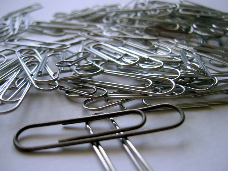 a pile of silver paper clips lying next to each other