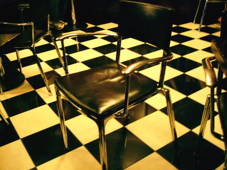 a couple of chairs and table on a checkered floor