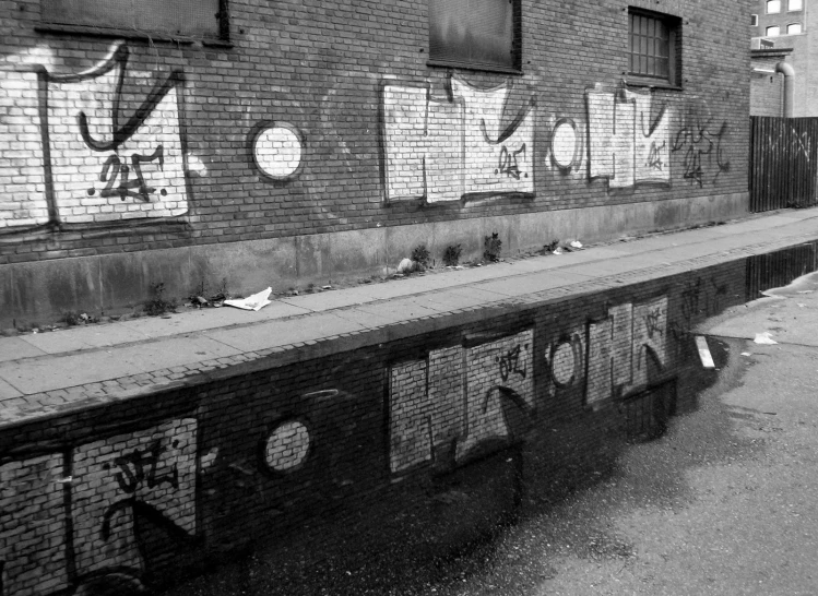 black and white pograph of the street scene with graffiti on the side of a building