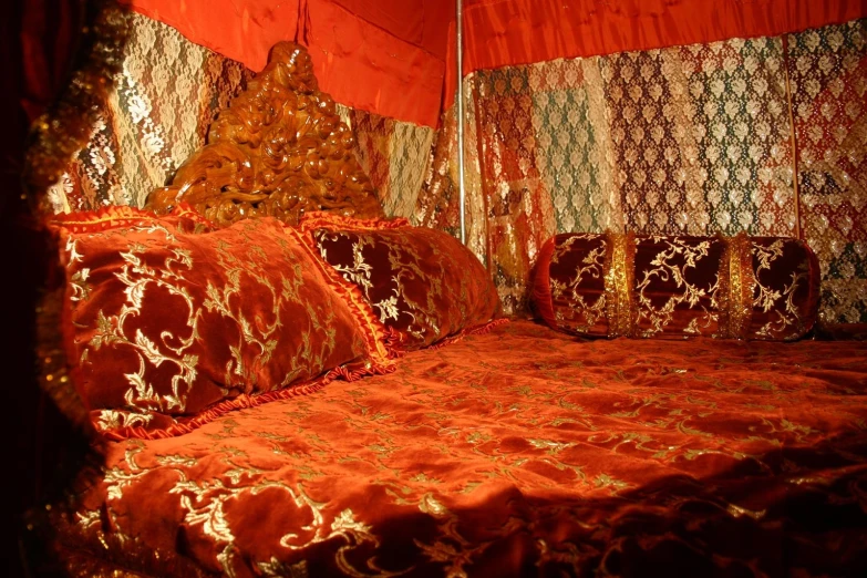 a red and gold covered bed with four pillows