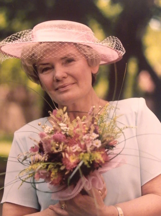 a woman with a bouquet wearing a pink hat