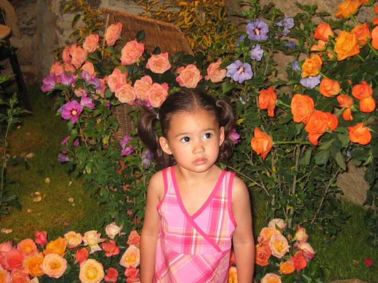 a little girl stands in front of flowers