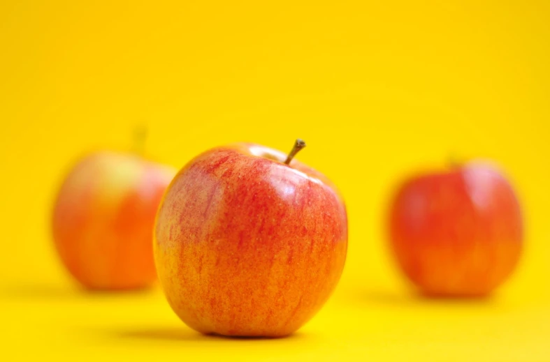 two red apples with a yellow background