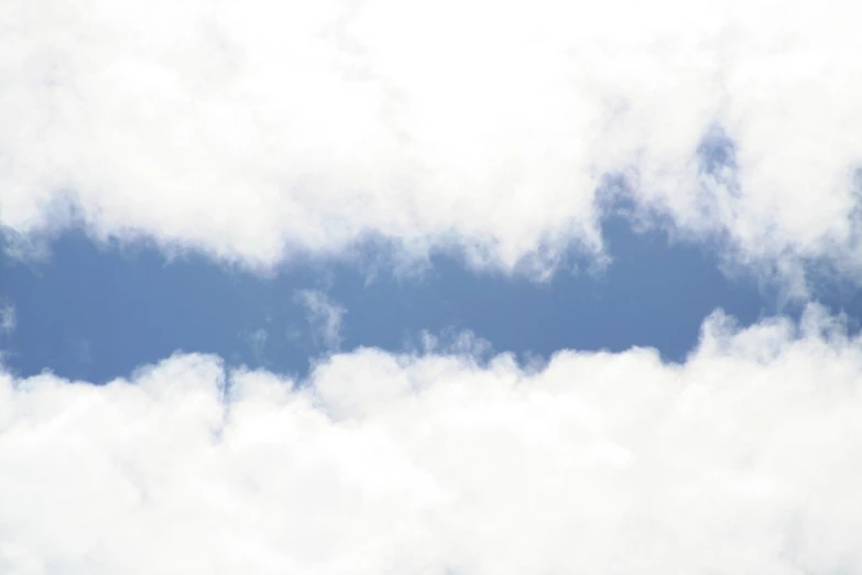 the sky has clouds and an airplane flying in the distance