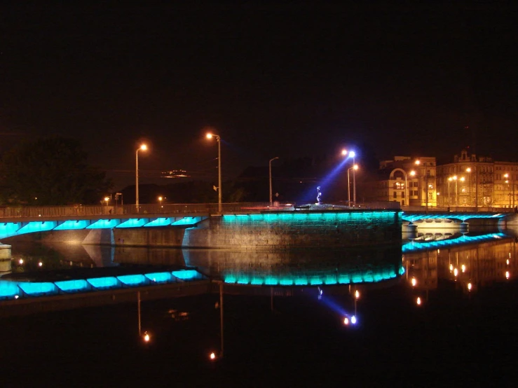 an artificial light structure glows across a dark river