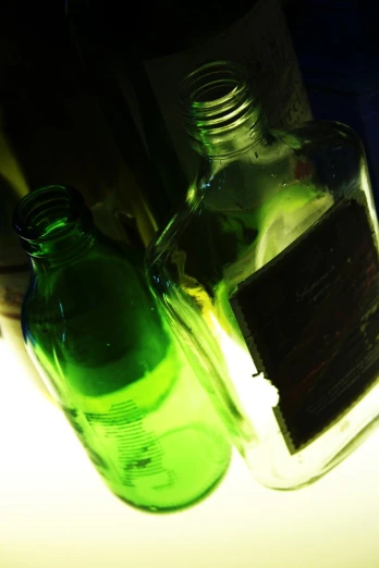 two green bottle are on a table next to wine bottles
