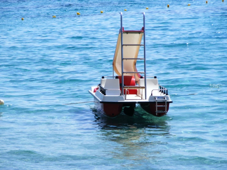 an empty white boat floating on top of blue water