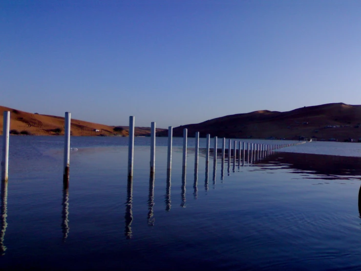 poles sticking out of the water in the desert