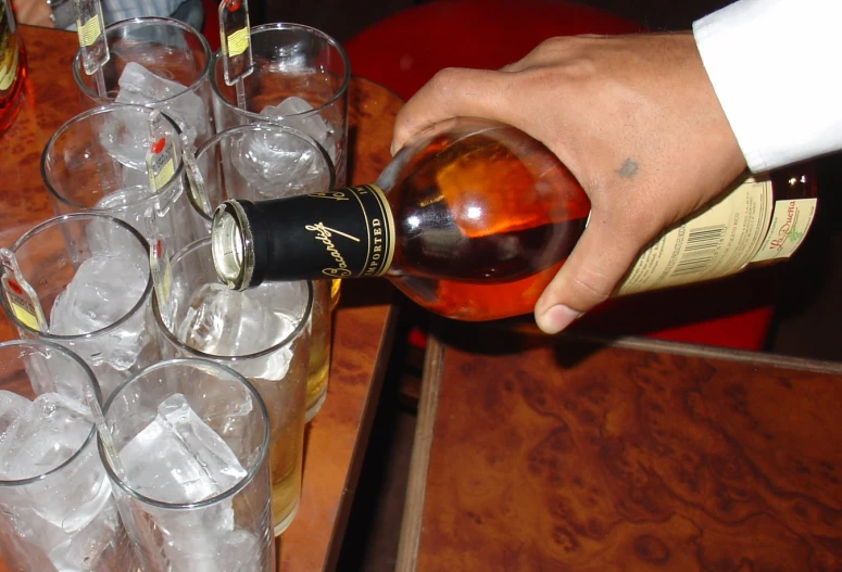 a man with a red and white shirt pouring a glass with some wine