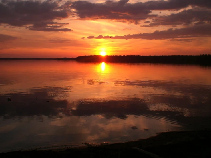 a sunset reflecting off the water in a lake