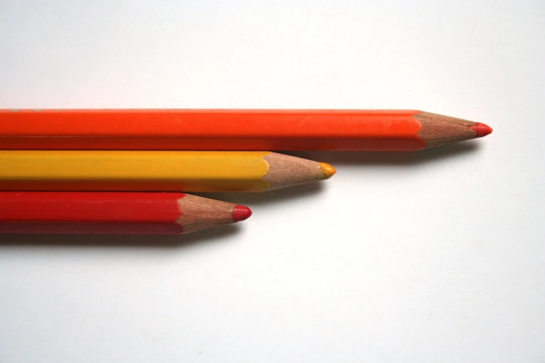 three yellow and red pencils next to each other