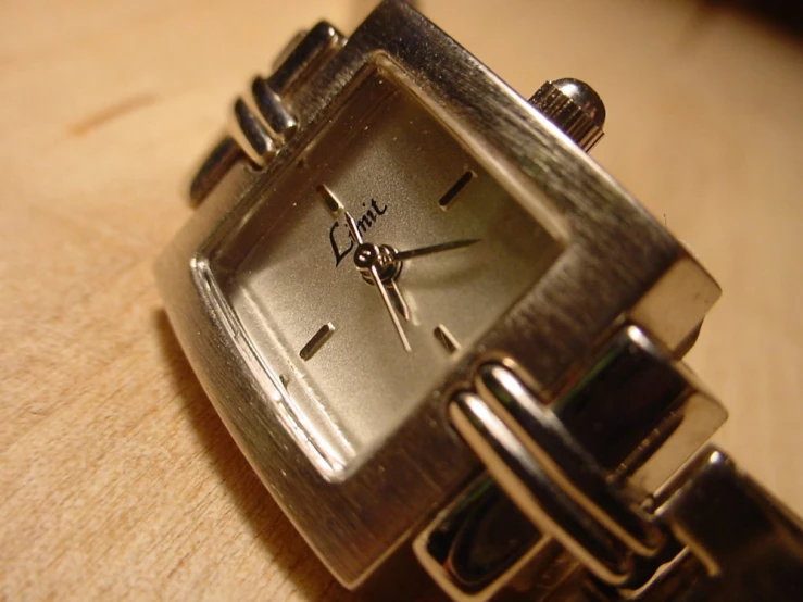 a close up of a watch on a wooden surface