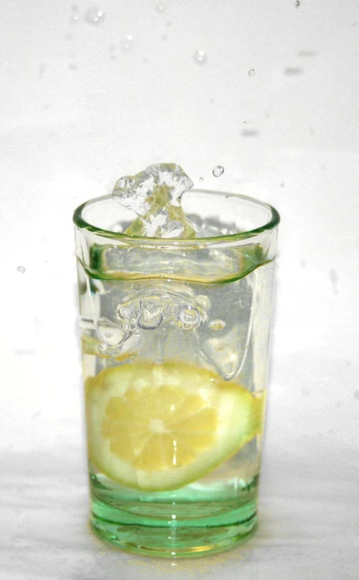 a lemon and ice cube in a glass with water