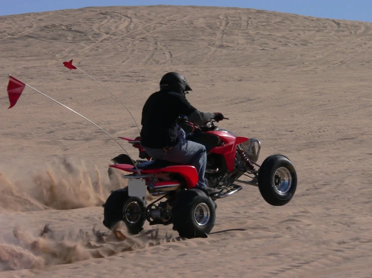 a man riding an atv on the sand