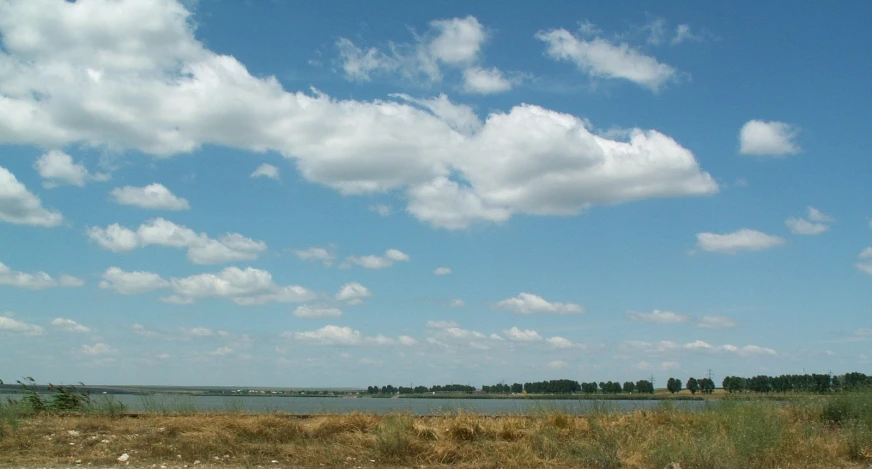 a cloudy blue sky hangs over a small lake