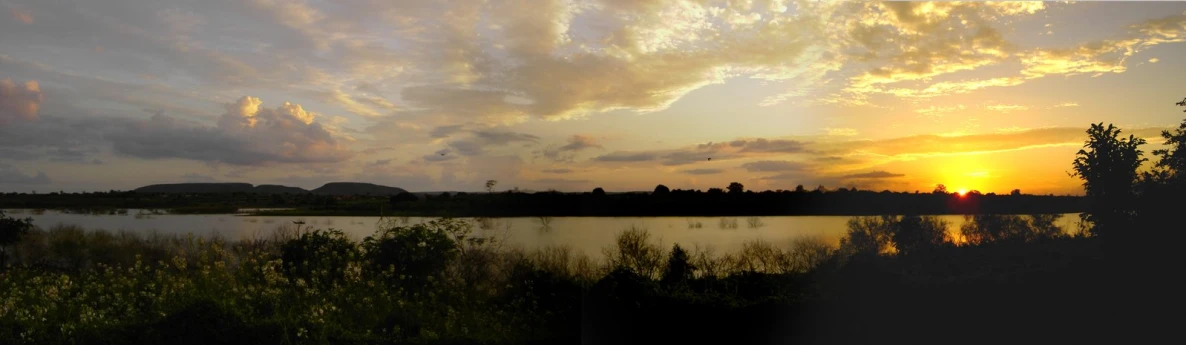 a lake surrounded by lush green grass at sunset