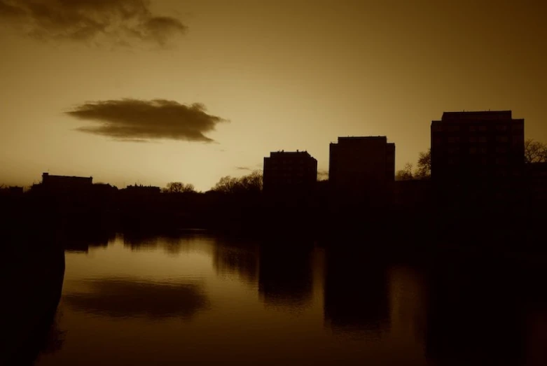 there is a building on the water with a dark sky behind it