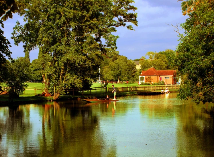 trees line the bank of a river that is surrounded by lush green hills