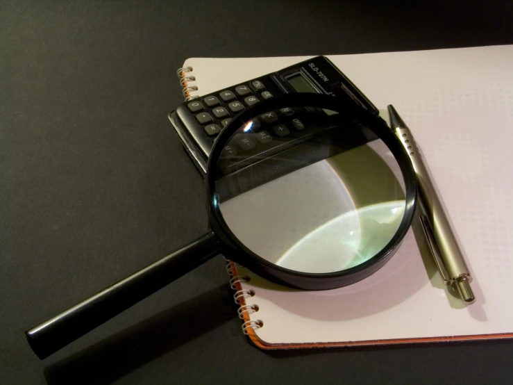 a pair of sunglasses laying on top of a piece of paper next to a pen