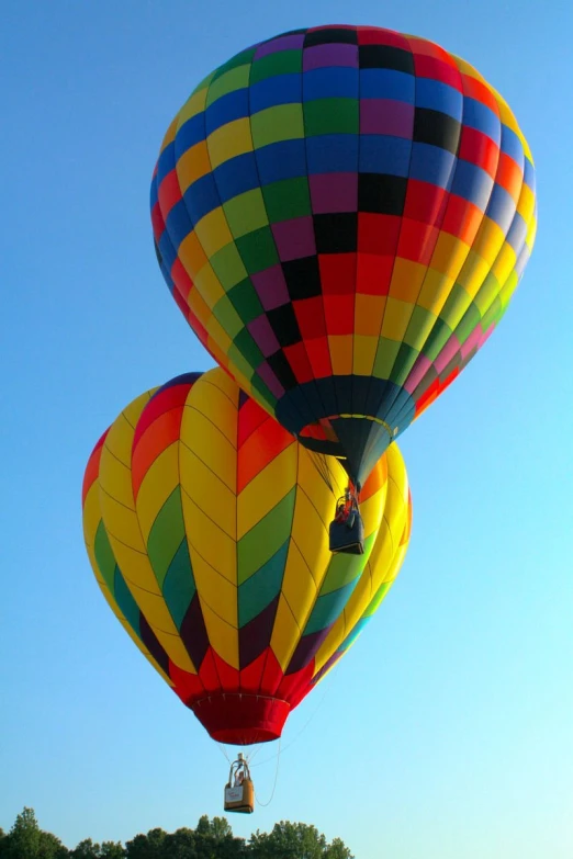 two large  air balloons with trees in the background