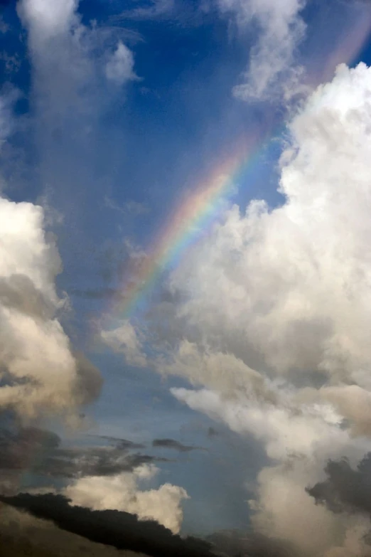 a rainbow in the sky with fluffy clouds