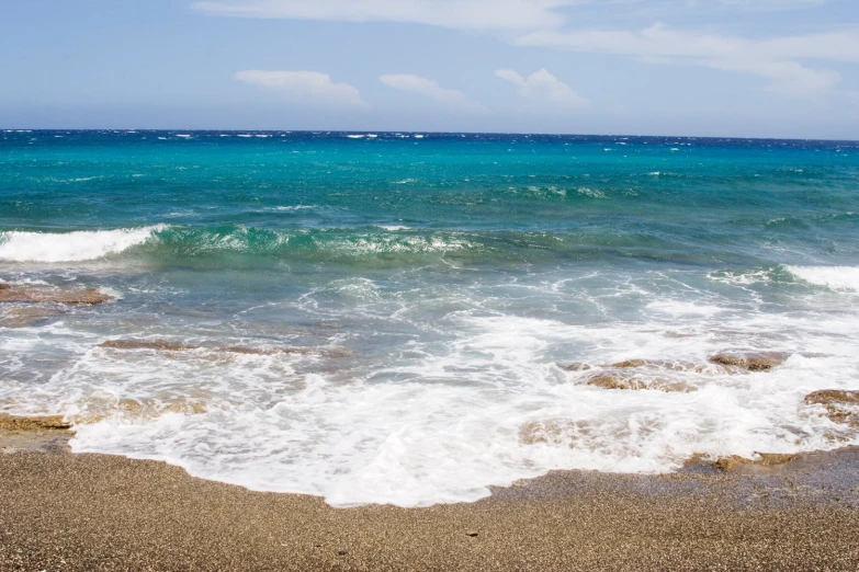 the waves wash on the beach while the sky looms over the horizon