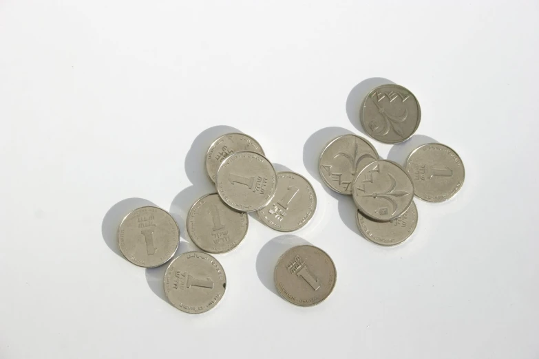 a white surface is shown with several coins and one has a dollar coin sticking out of it