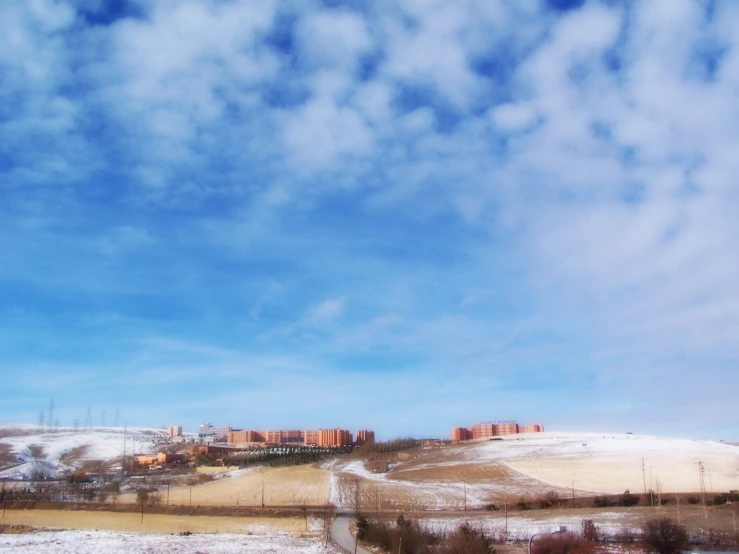 some white clouds in the blue sky and a hill