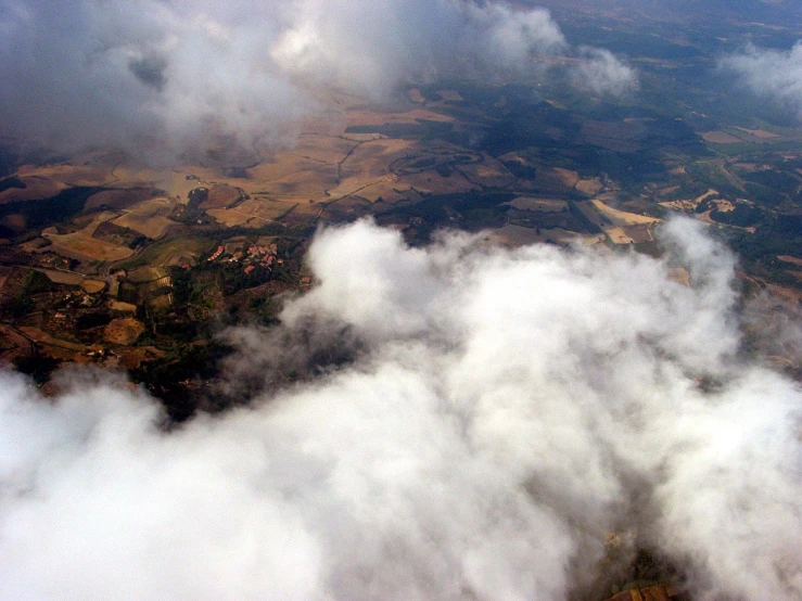 some clouds floating around the ground and mountains