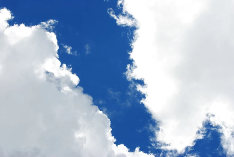 an airplane flying through the sky with some clouds