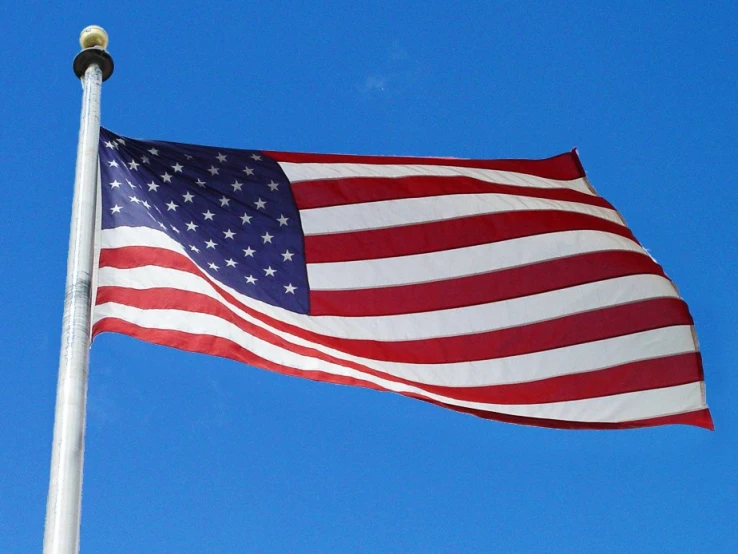 an american flag on top of a white pole