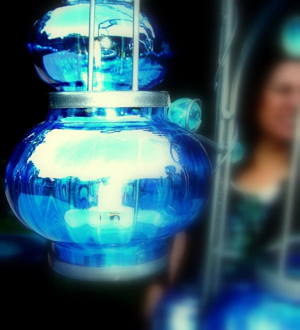 a blue glass vase with the reflection of a woman