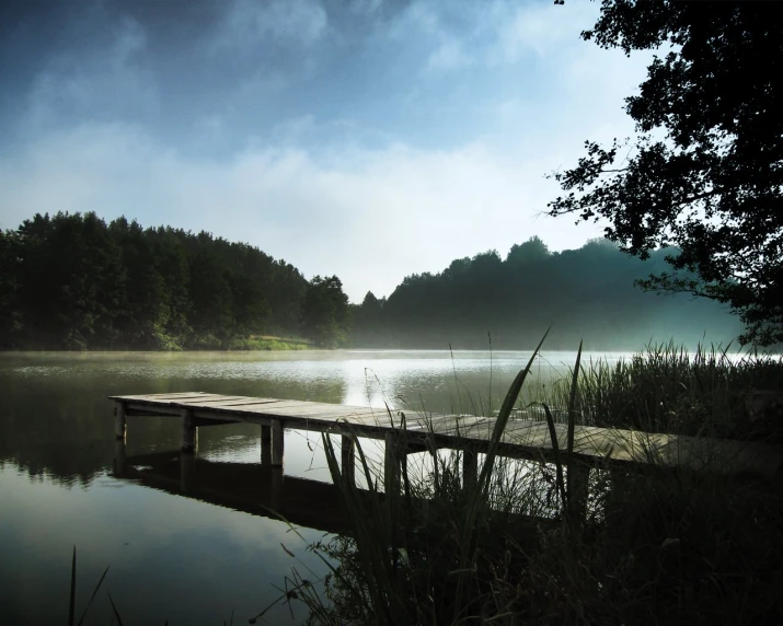 a dock is next to a misty lake